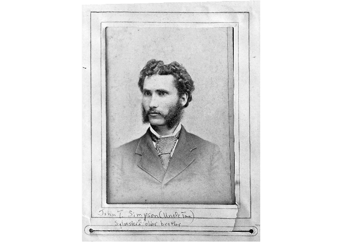 A vintage black and white portrait of a person with curly hair and distinctive sideburns wearing a suit and tie. Description generated by AI
